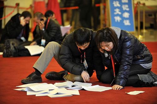 3月5日，第十一屆全國人民代表大會(huì)第五次會(huì)議在北京人民大會(huì)堂開幕。這是記者跪在地上查閱剛剛領(lǐng)到的相關(guān)材料。新華社記者 王鵬 攝 